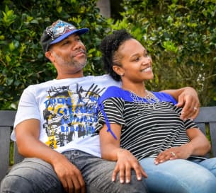 a couple sitting on a bench embracing each others with big smiles on their faces